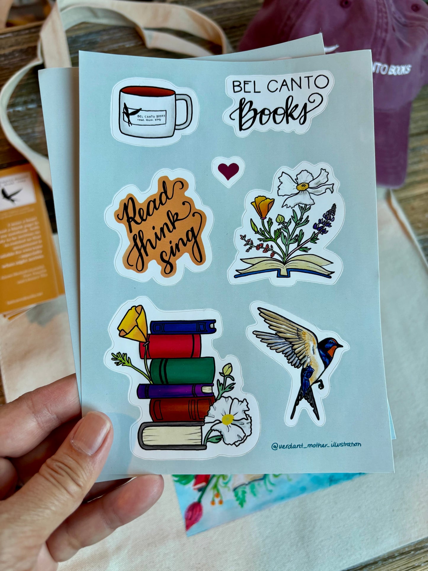 Bel Canto Books 5" x 7" vinyl sticker sheet, featuring hand-drawn illustrations by @verdant_mother_illustration, with 7 kiss-cut stickers, including a Bel Canto Books mug, "Read. Think. Sing." tagline, an open book with California poppies and other native flowers blooming out of it, a stack of books with California natives, and a swallow in flight