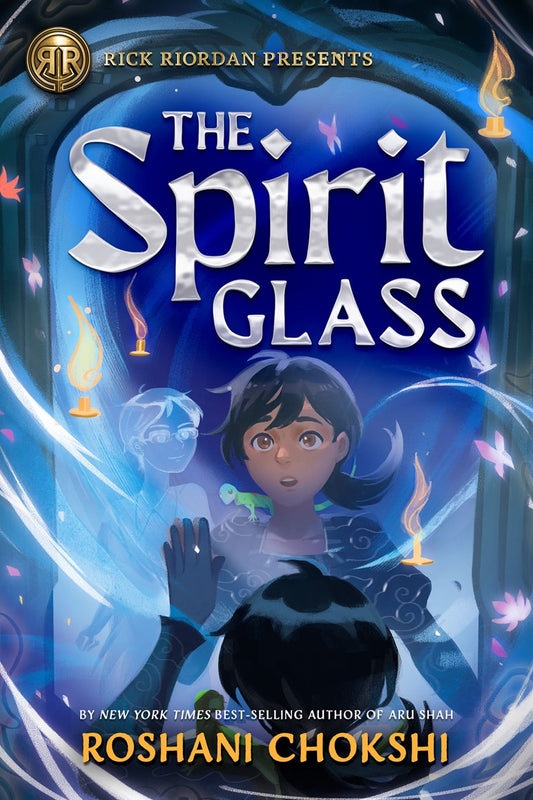 Book cover of 'The Spirit Glass' by Roshani Chokshi with a young dark haired girl looking into a mirror with a ghost inside, floating candles, and a blue and purple color scheme.